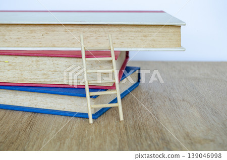 Small wooden ladder with books on wooden table representing study and knowledge, with customizable space for text. Small wooden ladder with books on wooden table representing study and knowledge, with customizable space for text. 139046998