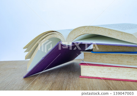 Open book with stacked books on wooden table representing study and research, with customizable space for text. Open book with stacked books on wooden table representing study and research, with customizable space for text. 139047003