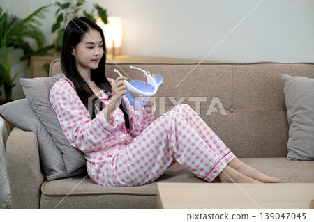 Asian woman adult pajamas using light therapy device home self care wellness beauty treatment facial mask for relaxation comfort living room Asian woman adult pajamas using light therapy device home self care wellness beauty treatment facial mask for relaxation comfort living room 139047045