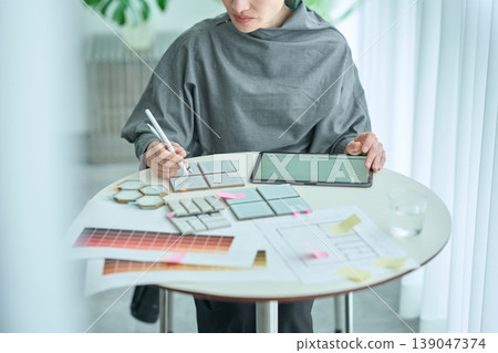 A female designer checks material samples and color charts. 139047374
