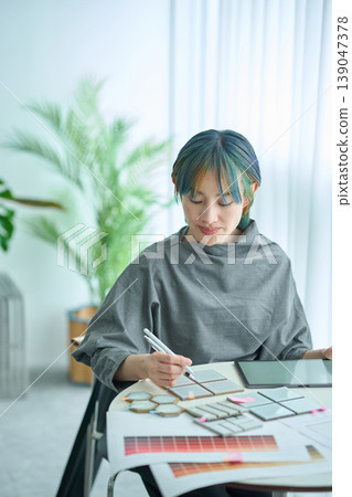 A female designer checks material samples and color charts. A female designer checks material samples and color charts. 139047378