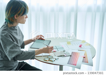 A female designer checks material samples and color charts. A female designer checks material samples and color charts. 139047381