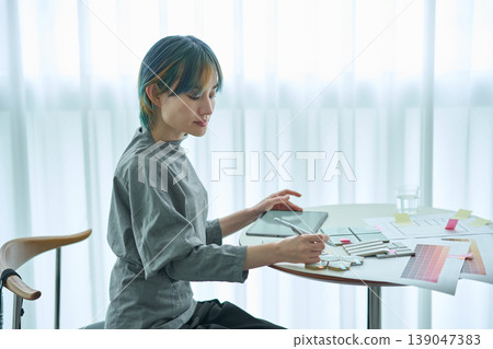 A female designer checks material samples and color charts. A female designer checks material samples and color charts. 139047383