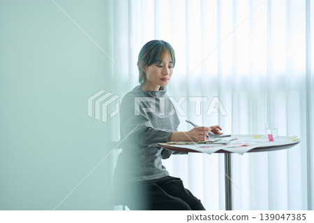 A female designer checks material samples and color charts. 139047385