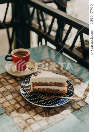 Delicious cake on a plate and a cup of coffee in a cafe. Daylight. Delicious cake on a plate and a cup of coffee in a cafe. Daylight. 139047760