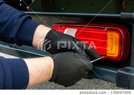 Mechanic hands fixing rear lamp on truck Mechanic hands fixing rear lamp on truck 139047809