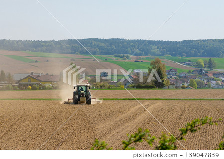 Tractor working in dry field kicking up dust 139047839