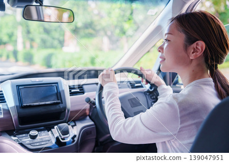 一位年輕女子微笑著開車。 一位年輕女子微笑著開車。 139047951