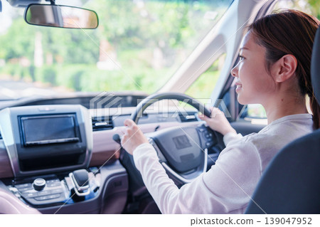 一位年輕女子微笑著開車。 一位年輕女子微笑著開車。 139047952