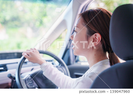 一位年輕女子微笑著開車。 139047960