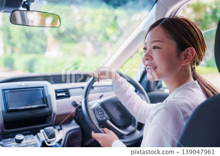 一位年輕女子微笑著開車。 139047961