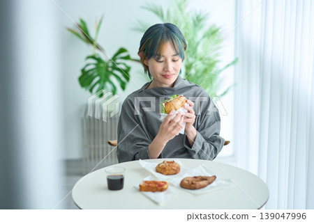 A woman eating a sandwich indoors A woman eating a sandwich indoors 139047996