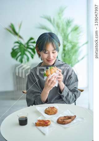 A woman eating a sandwich indoors A woman eating a sandwich indoors 139047997