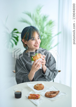 A woman eating a sandwich indoors 139048000