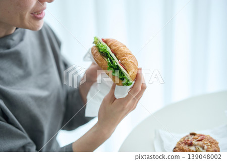 A woman eating a sandwich indoors A woman eating a sandwich indoors 139048002