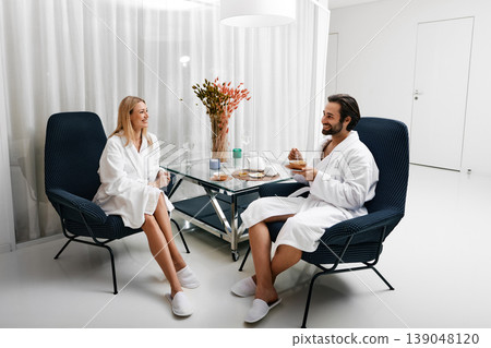 Relaxed beautiful couple with healthy tea communicate while relaxing in lounge area of wellness center after spa treatments Relaxed beautiful couple with healthy tea communicate while relaxing in lounge area of wellness center after spa treatments 139048120