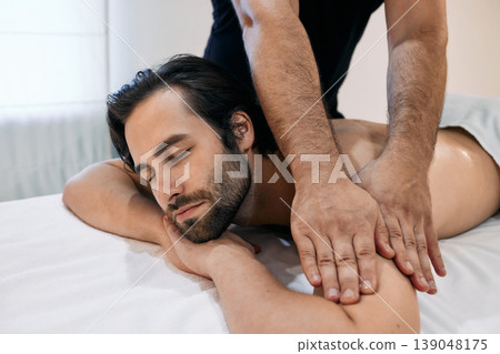 Handsome man getting relax massage on spa treatment in wellness centre. Massage therapy for male client Handsome man getting relax massage on spa treatment in wellness centre. Massage therapy for male client 139048175