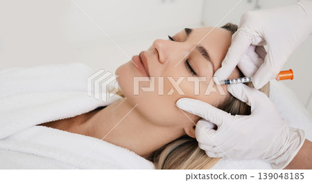 Beautiful woman during facial mesotherapy for smoothing of mimic wrinkles around eyes with beautician. Anti-aging injections for rejuvenation and lift skin Beautiful woman during facial mesotherapy for smoothing of mimic wrinkles around eyes with beautician. Anti-aging injections for rejuvenation and lift skin 139048185