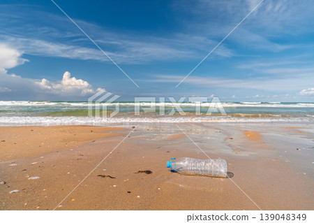 The sea returns plastic to the shore, an empty bottle washed up on a clean beach, sunny weather on the ocean shore, copy space for text. The sea returns plastic to the shore, an empty bottle washed up on a clean beach, sunny weather on the ocean shore, copy space for text. 139048349