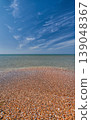 shell beach and a calm, clear sea, copy space. A concept for advertising a vacation on the magnificent beaches of the Mediterranean, a sky with wispy clouds 139048367