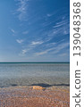 vertical poster with a view of a calm, warm sea from a shell beach, a high sky with wispy clouds, a concept for advertising a seaside vacation 139048368