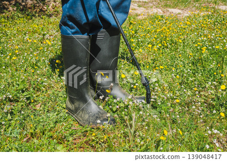 a spray nozzle releases herbicide on weeds 139048417