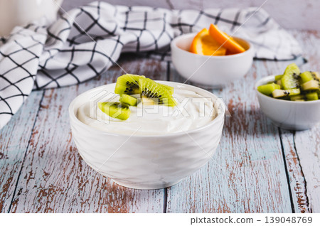 Thick fermented skim milk product with probiotics and kiwi in a bowl on the table Thick fermented skim milk product with probiotics and kiwi in a bowl on the table 139048769