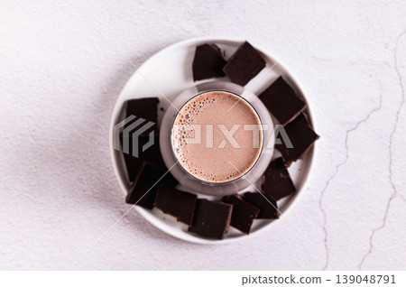 Close up of warm cocoa drink in a glass and chocolate on a plate on the table top view 139048791