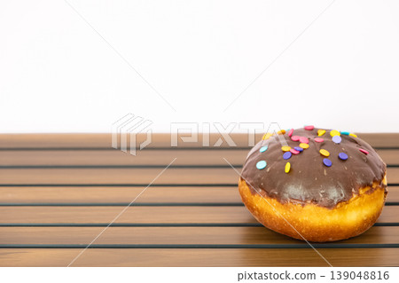 A chocolate doughnut with chocolate glaze, sprinkled with colorful rainbow sprinkles. A chocolate doughnut with chocolate glaze, sprinkled with colorful rainbow sprinkles. 139048816