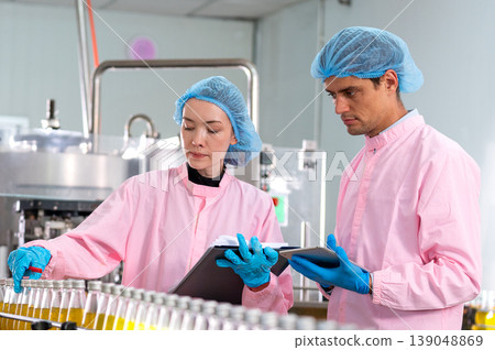 Close up the woman factory worker discuss with technician man about the quality of the drinking product in the industrial factory and stay in the line of product management machine. 139048869