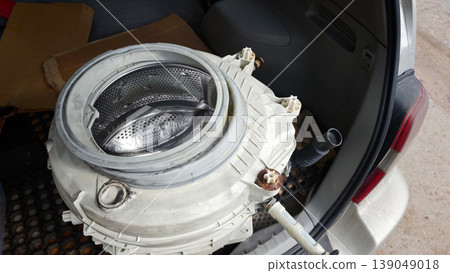 Old washing machine drum placed inside a car trunk during repair process Old washing machine drum placed inside a car trunk during repair process 139049018