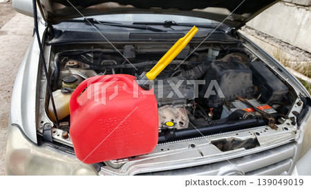 Gas can and car engine scene during a repair task in a garage on a sunny day Gas can and car engine scene during a repair task in a garage on a sunny day 139049019
