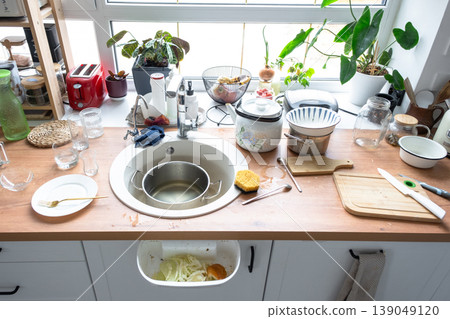 Messy kitchen, dirty dishes in sink, cluttered countertop, food scraps, kitchen chaos, untidy home scene, unwashed utensils, real life disorder. Messy kitchen, dirty dishes in sink, cluttered countertop, food scraps, kitchen chaos, untidy home scene, unwashed utensils, real life disorder. 139049120