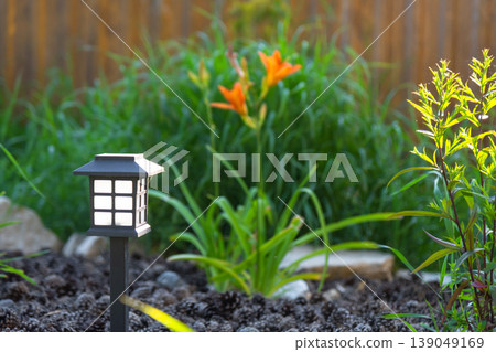 Modern LED garden lantern, daylily and ornamental grass mix, mulch bed, large rocks, eco-friendly flower border, contemporary minimalist landscape. Modern LED garden lantern, daylily and ornamental grass mix, mulch bed, large rocks, eco-friendly flower border, contemporary minimalist landscape. 139049169