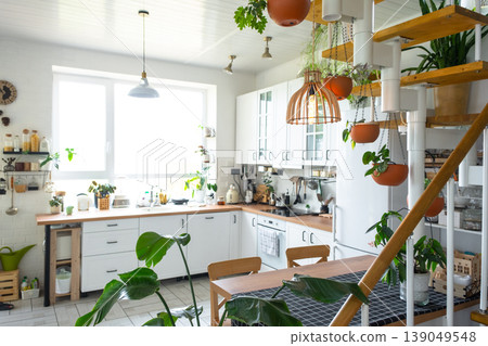 Open plan kitchen, modular staircase, many houseplants, natural daylight, wooden accents, eco-friendly, green and white, organized modern home style. Open plan kitchen, modular staircase, many houseplants, natural daylight, wooden accents, eco-friendly, green and white, organized modern home style. 139049548