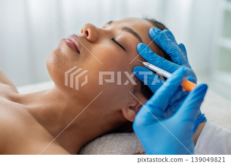 Closeup of young African American woman receiving facial injection treatment in clinic Closeup of young African American woman receiving facial injection treatment in clinic 139049821