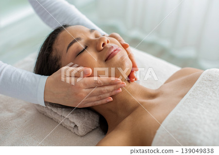 Young African American woman relaxing with eyes closed during facial massage 139049838
