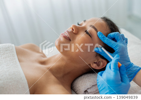 Closeup of young black woman receiving cosmetic forehead injection at spa clinic Closeup of young black woman receiving cosmetic forehead injection at spa clinic 139049839