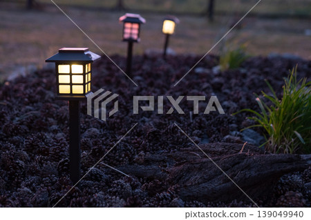 Decorative lantern for flowerbed, solar powered, garden accent lighting, ornamental grasses and mulch, modern landscape design style. Decorative lantern for flowerbed, solar powered, garden accent lighting, ornamental grasses and mulch, modern landscape design style. 139049940