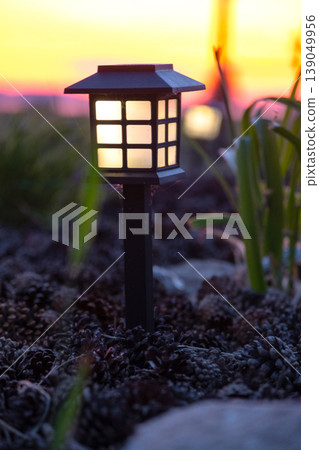 Decorative solar garden lantern in flowerbed, mixed perennials and ornamental grasses, modern sustainable landscape design, soft mulch ground. Decorative solar garden lantern in flowerbed, mixed perennials and ornamental grasses, modern sustainable landscape design, soft mulch ground. 139049956