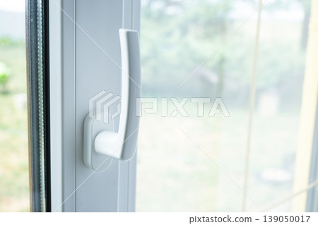 Window handle detail, PVC window closed, focusing on hardware and fittings, efficient insulation, secure closing, prep for ventilation, energy saving. 139050017