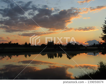 Beautiful sunset over a calm river with perfect sky reflection in the water. Beautiful sunset over a calm river with perfect sky reflection in the water. 139050074