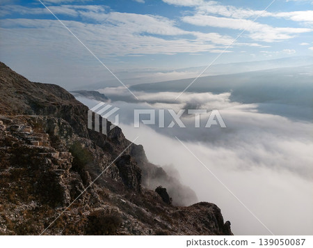 Panoramic view from a rocky mountain peak over a thick sea of clouds in the valley. Panoramic view from a rocky mountain peak over a thick sea of clouds in the valley. 139050087
