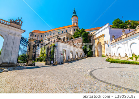 The Mikulov castle, Czech republic. Famous medieval castle on top of hill. Beautiful ornament garden with flowers, trees and green grass. Summer weather and blue sky. Beautiful wine region near Palava The Mikulov castle, Czech republic. Famous medieval castle on top of hill. Beautiful ornament garden with flowers, trees and green grass. Summer weather and blue sky. Beautiful wine region near Palava 139050192