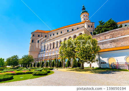 The Mikulov castle, Czech republic. Famous medieval castle on top of hill. Beautiful ornament garden with flowers, trees and green grass. Summer weather and blue sky. Beautiful wine region near Palava The Mikulov castle, Czech republic. Famous medieval castle on top of hill. Beautiful ornament garden with flowers, trees and green grass. Summer weather and blue sky. Beautiful wine region near Palava 139050194