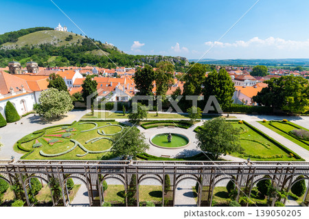 Aerial panorama of Mikulov city, czech republic. The tower of St Wenceslas in foreground. "Svaty kopec" hill with St Sebastian chapel in background. Look to town roofs, summer day. Aerial panorama of Mikulov city, czech republic. The tower of St Wenceslas in foreground. "Svaty kopec" hill with St Sebastian chapel in background. Look to town roofs, summer day. 139050205