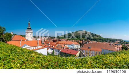 Aerial panorama of Mikulov city, czech republic. The tower of St Wenceslas in foreground. "Svaty kopec" hill with St Sebastian chapel in background. Look to town roofs, summer day. Aerial panorama of Mikulov city, czech republic. The tower of St Wenceslas in foreground. "Svaty kopec" hill with St Sebastian chapel in background. Look to town roofs, summer day. 139050206