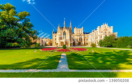 Panoramic view of famous Lednice castle, Czech Republic. Front view with beautiful flowers and green grass. Part of UNESCO heritage. Summer day, with blue sky. 139050208