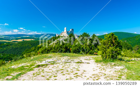 The old ruins of castle Cachtice (Cachtice in local speak). Ruined castle on top of hill at Slovakia. Famous and mysterious place known from legend of blood lady Bathory. Summer day, panorama view. The old ruins of castle Cachtice (Cachtice in local speak). Ruined castle on top of hill at Slovakia. Famous and mysterious place known from legend of blood lady Bathory. Summer day, panorama view. 139050289