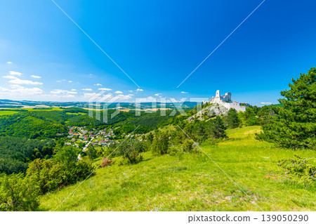 The old ruins of castle Cachtice (Cachtice in local speak). Ruined castle on top of hill at Slovakia. Famous and mysterious place known from legend of blood lady Bathory. Summer day, panorama view. The old ruins of castle Cachtice (Cachtice in local speak). Ruined castle on top of hill at Slovakia. Famous and mysterious place known from legend of blood lady Bathory. Summer day, panorama view. 139050290